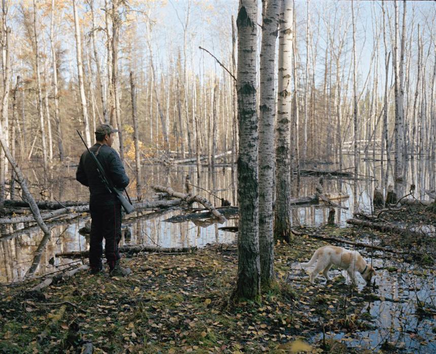 Willard Bittern, and his dog Buster, at the edge of a stand of poplar trees flooded by a beaver dam